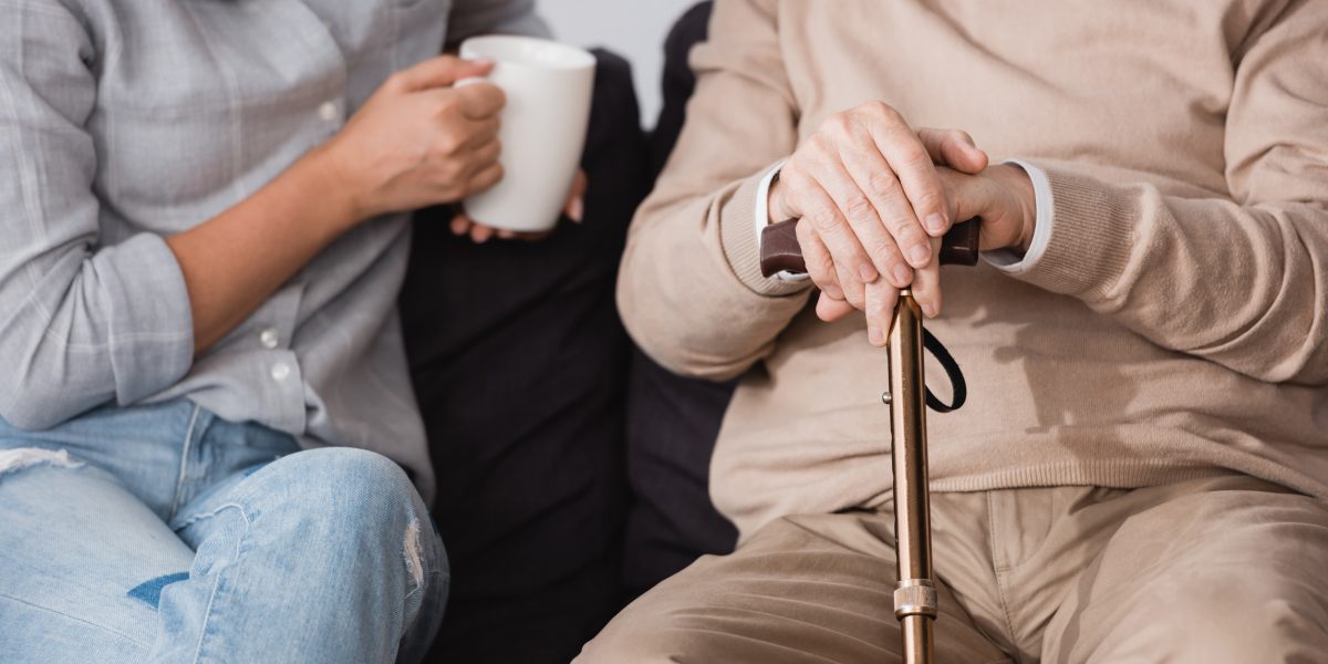 partial view of woman with cup of tea near aged father at home, banner